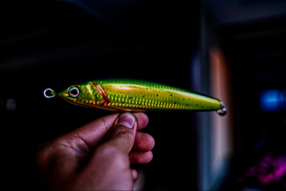 Person choosing a green crankbait lure from a tackle box.