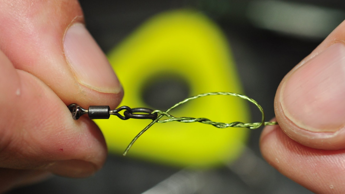Person tying a clinch knot to a swivel with braided line.