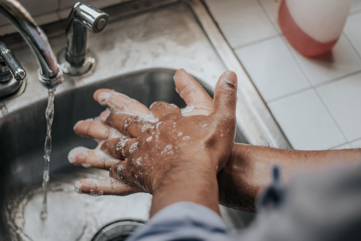 Man washing hands with soap under running water.