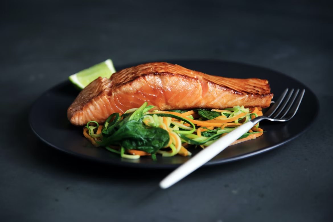 Skinned salmon fillet on a plate with salad and a fork.