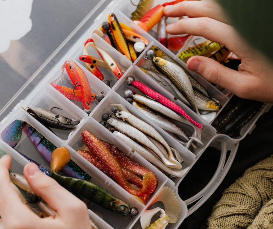 Tackle box with fishing lures and hooks on a table.