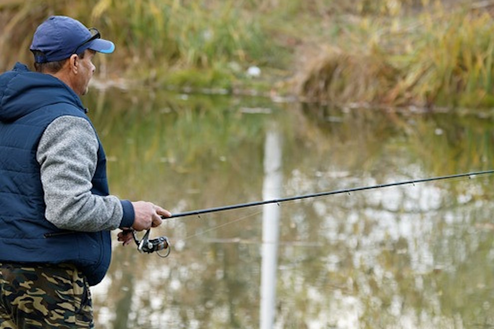 Man using a spinning rod in a small pond.