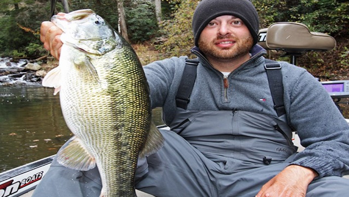 Angler holding a big spotted bass on a boat.