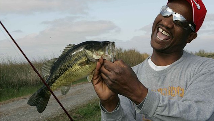 Fisherman releasing a spotted bass back into the water.